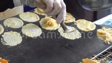 在夜市瑶华拉道上用椰子片烹制异国风味的泰国薄煎饼或烤面包的过程